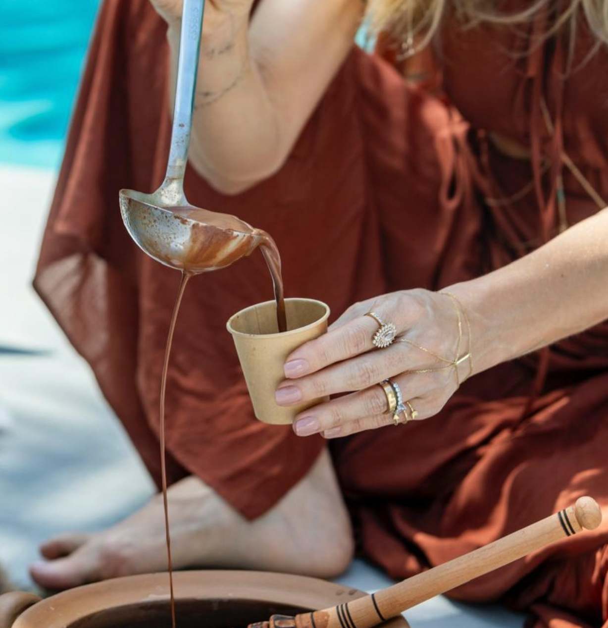 Marjorie pouring ceremonial cacao from a ladle into a cup